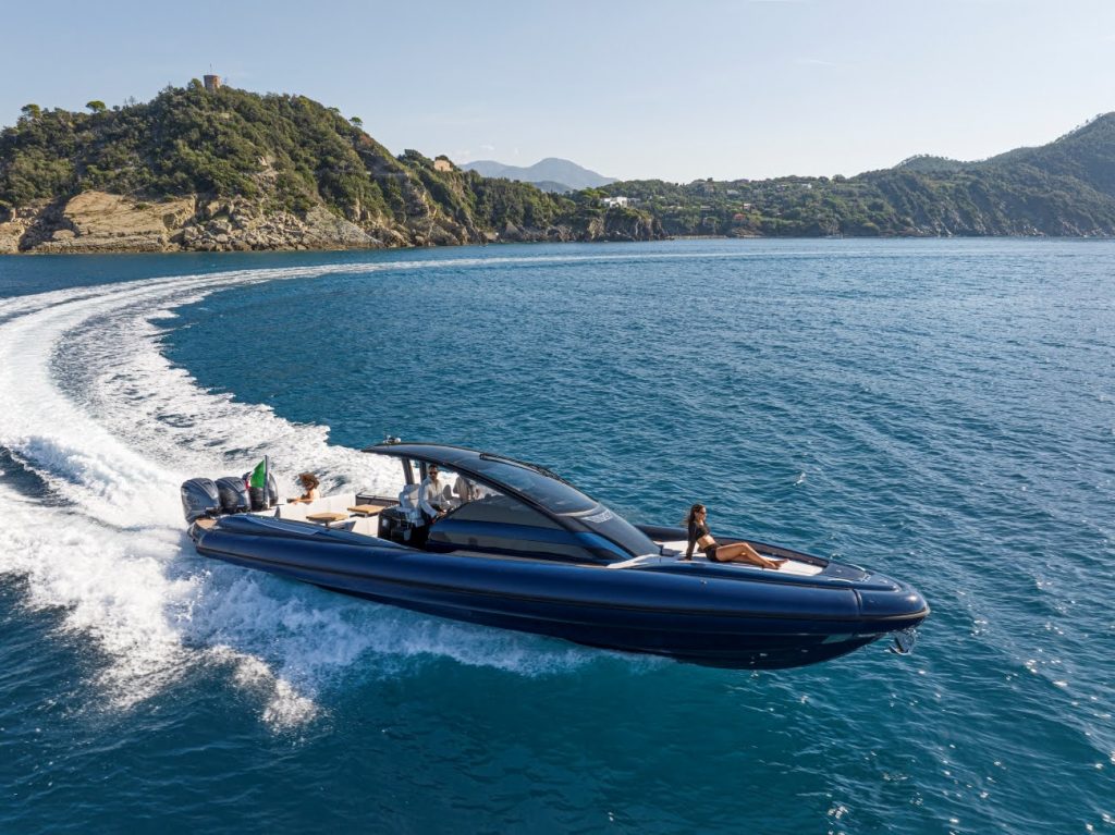 Un grande RIB blu con tre motori sfreccia attraverso la baia.